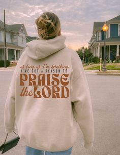 a woman walking down the street wearing a sweatshirt that says praise the lord