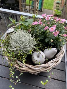 a basket filled with flowers and plants on top of a wooden table