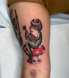 a tattoo on the arm of a person with a guitar and toad sitting on top of a mushroom