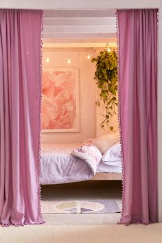 a bedroom with pink curtains and a white bed in the corner next to a potted plant