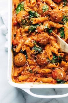 a white casserole dish filled with pasta and meatballs