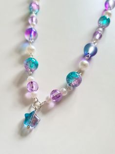 This purple galaxy inspired necklace has been handcrafted from stunning glass beads and faux pearls with a dangling star bead in the centre. Each bead is connected by handmade wire loops and the necklace is secured with a lobster clasp. It features a 2 inch extender chain so the necklace can be adjusted from 16 to 18 inches. Length: Approximately 16 inches + 2 inch extender chain. Materials: Glass and plastic beads, silver plated copper wire, silver plated extender chain and clasp. How to care f Galaxy Aesthetic Purple, Purple Beads Necklace, Purple Cosmos, Galaxy Aesthetic, Purple Bead Necklace, Aesthetic Purple, Necklace Bead, Bead Chain, Handmade Wire