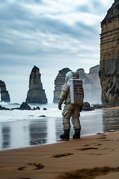 an astronaut walking on the beach next to some rocks