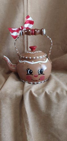 a teapot with a bow on it is sitting on a cloth covered tablecloth