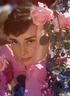 black and white photograph of a woman with flowers in her hair, leaning against a tree