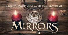 two red candles sitting on top of a wooden table next to a mirror with the words mirrors above it