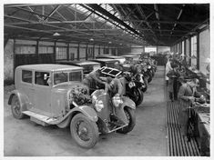 an old black and white photo of men working on cars