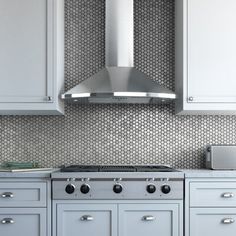 a stove top oven sitting inside of a kitchen next to white cupboards and drawers