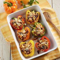 peppers stuffed with meat and vegetables in a white casserole dish on a wooden table
