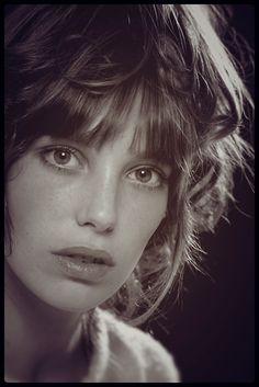 a close up of a woman with short hair and blue eyes looking at the camera