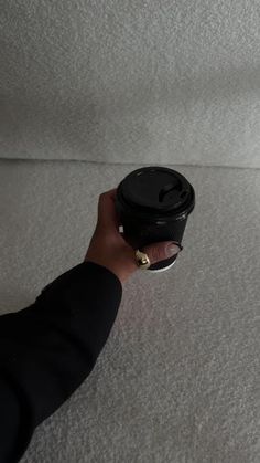 a hand holding a coffee cup on top of a white carpeted floor in a living room
