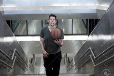 a man holding a basketball in his hand while walking down an escalator stock photo