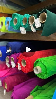 many colors of fabric are on display in a store with price tags attached to them