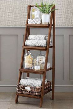 a wooden ladder shelf with towels and other bathroom items on the shelves next to it