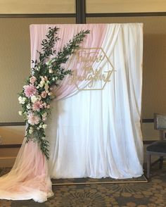 a pink and white wedding arch decorated with greenery, carnations and flowers