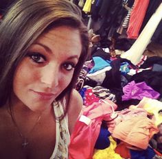 a woman is looking at the camera in front of clothes