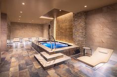 a spa room with a hot tub and lounge chairs