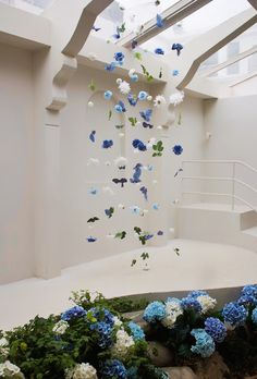 blue and white flowers floating in the air next to a staircase with skylights above