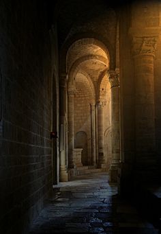 an alley way with stone walls and arches at night, lit by a street lamp