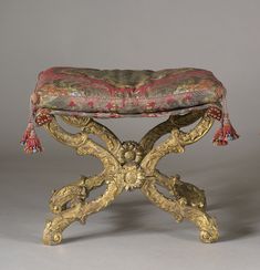 an ornately decorated bench with tassels on it's legs and foot rest