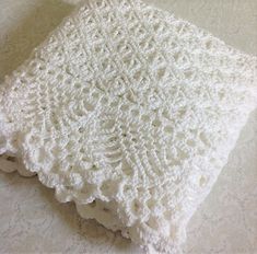 a white crocheted blanket sitting on top of a table