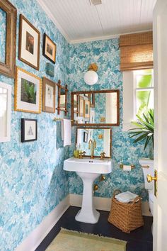 a bathroom with blue wallpaper and pictures on the walls