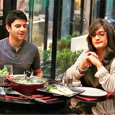 two people sitting at a table with food in front of them