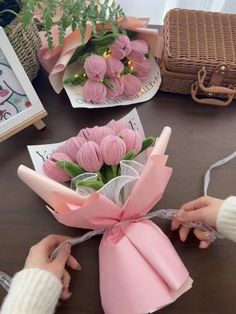 someone is wrapping flowers in pink paper on a table