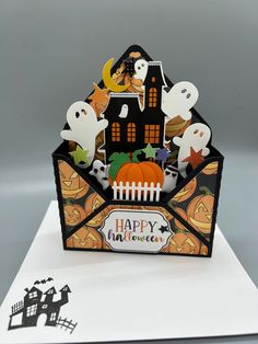 an open halloween card with ghost, pumpkins and house on it's side