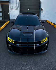 a black sports car parked in front of a garage with yellow and white stripes on it