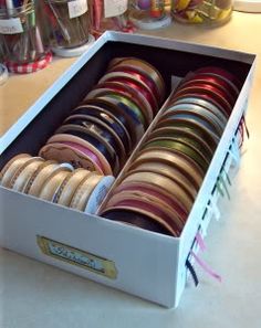 an open box filled with lots of different colored ribbons on top of a white counter