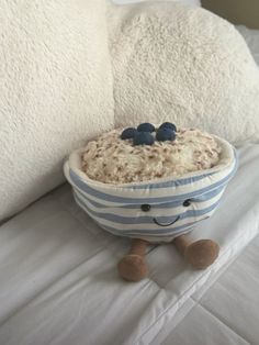 a bowl filled with rice and blueberries sitting on top of a white bed next to pillows