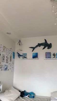 there is a bed with white sheets and shark decorations on the wall above it,