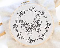 a cross stitch pattern with a butterfly in the center and leaves around it on a white background