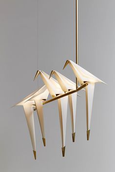 a group of birds hanging from a light fixture in the shape of an origami bird