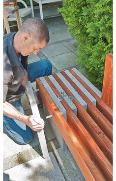 a man is working on some wooden benches in the yard with his hands and nails