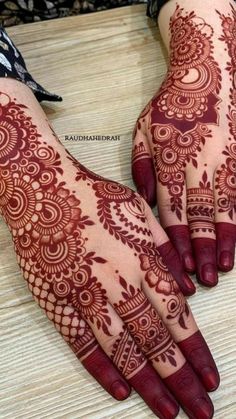 two hands with henna designs on them, one is red and the other is brown