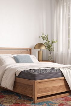 a bed with a wooden headboard and foot board in a white room next to a window