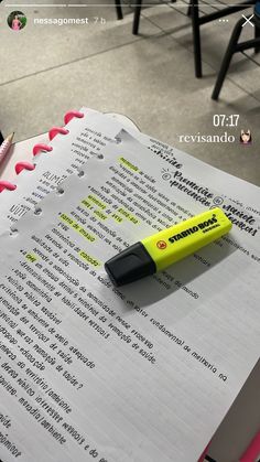 a yellow pen sitting on top of a book next to a black and white marker