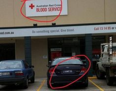 two cars parked in front of a building with a red cross sign on it's side