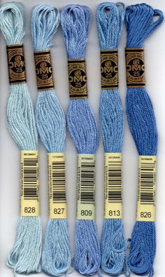 six skeins of blue yarn in different sizes and colors, with labels on them