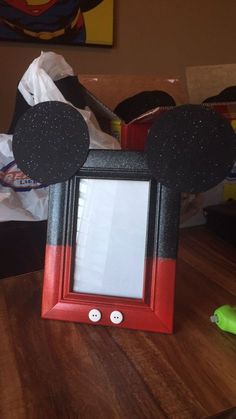 a mickey mouse photo frame sitting on top of a wooden table