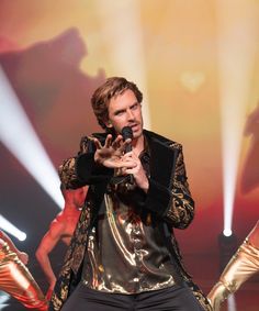 a man is performing on stage with his hands in the air