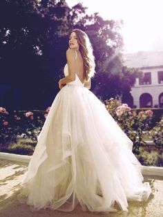 a woman in a wedding dress is standing outside