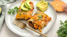 two enchiladas on a plate with avocado and cilantro