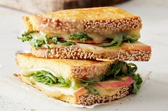 two sandwiches stacked on top of each other with lettuce, tomato and sesame seeds