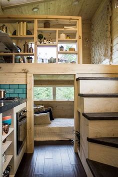 a tiny kitchen with stairs leading up to the top floor and loft bed above it