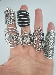 a person's hand holding five rings in different shapes and sizes, all on top of each other