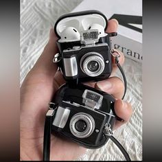 two small cameras sitting on top of each other in someone's hand next to a book