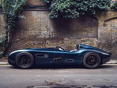 a blue sports car parked in front of a brick building with ivy growing on it